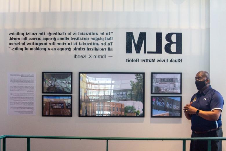 Dean of Students Cecil Youngblood stands in front of the new BLM photo gallery display in the Powerhouse. 