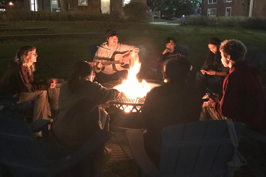 Students sitting around a bonfire.
