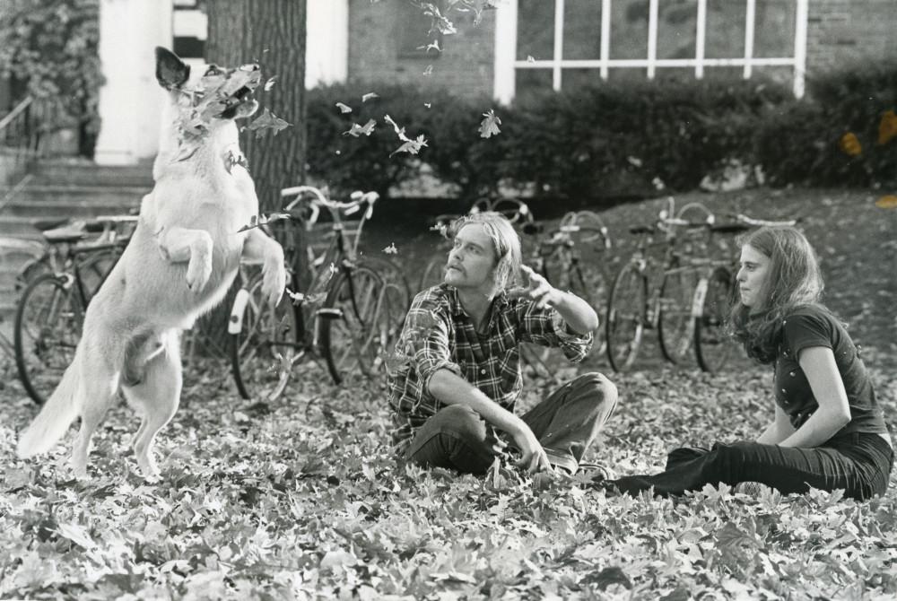 1976年秋天，两个学生和一只狗在学生会门前合影.